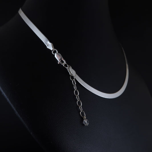 Silver flat chain necklace on a black surface