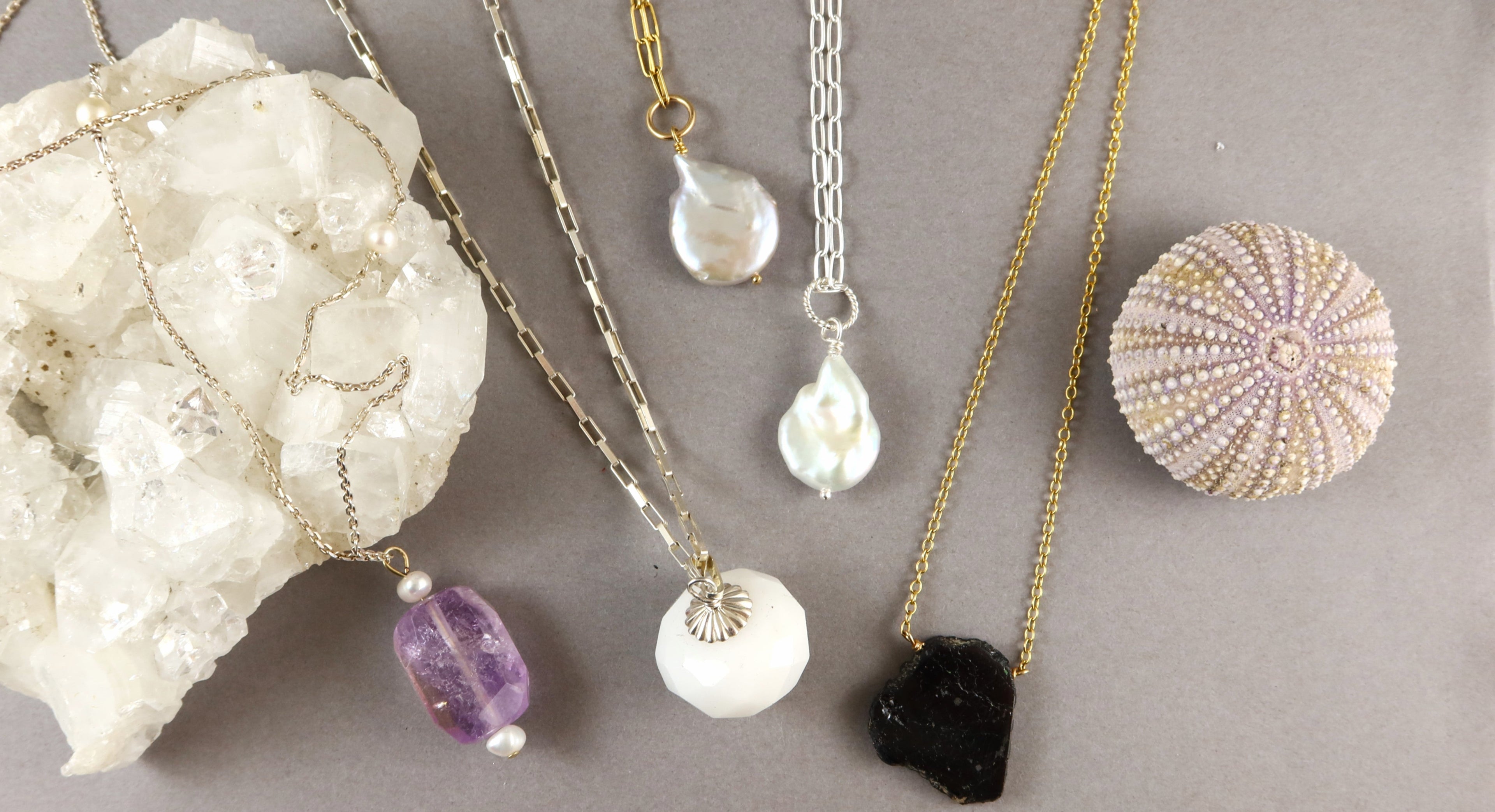 Jewelry set with necklaces and pendants on a gray surface with decorative stones.