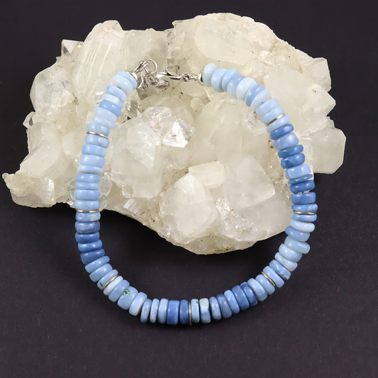 Blue beaded bracelet on a dark background with a white crystal rock.