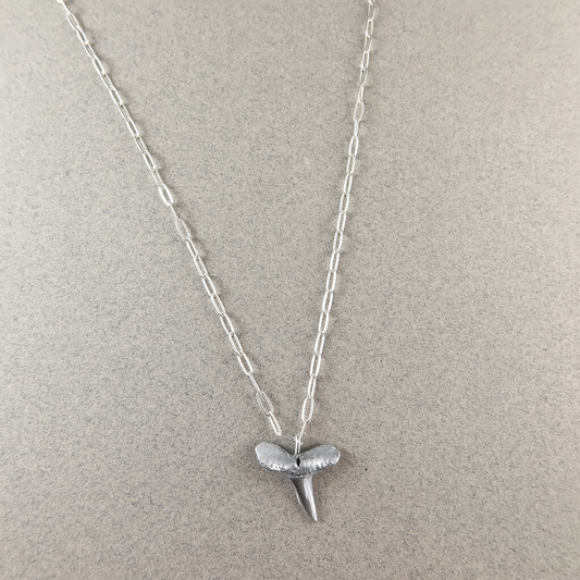Silver shark tooth necklace on a light gray background