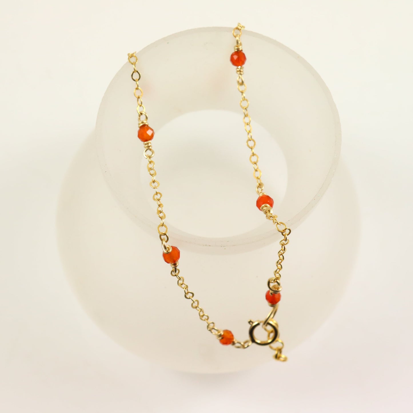 A gold-filled 14k chain bracelet with a faceted orange carnelian gemstone accent.