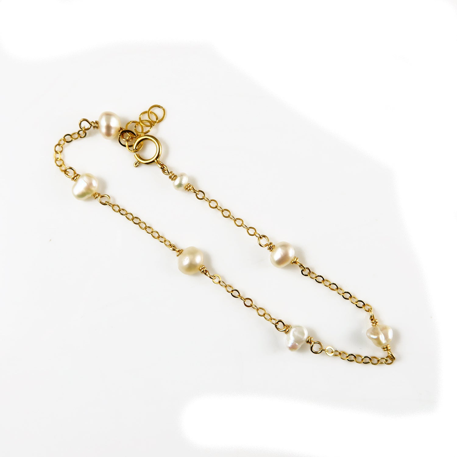 Gold chain bracelet with pearls on a white background