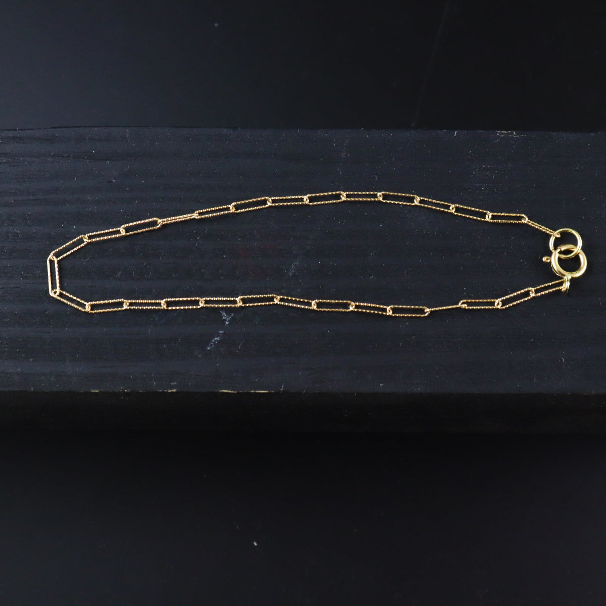 Gold chain necklace on a dark surface