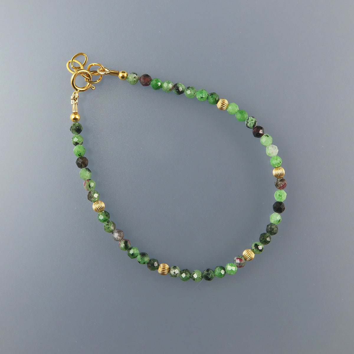 Ruby Beaded bracelet with green and gold accents on a gray background