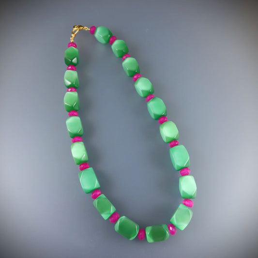 Necklace with green beads and pink accents on a gray background