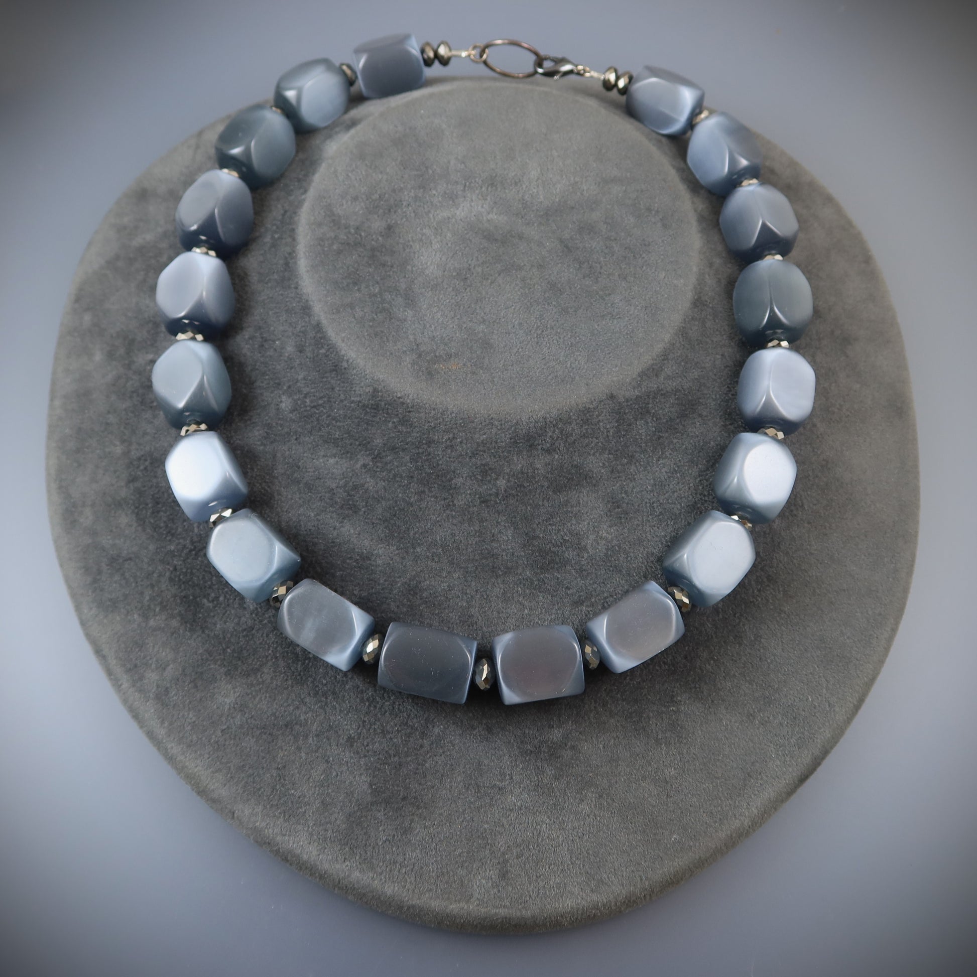 Necklace with gray and white beads on a gray surface
