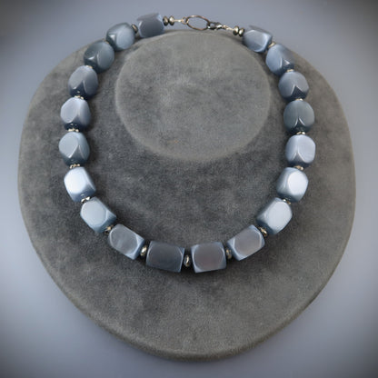 Necklace with gray and white beads on a gray surface