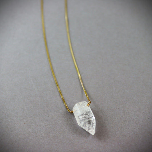 Gold filed  chain Necklace with a clear crystal quartz pendant on a dark gray background