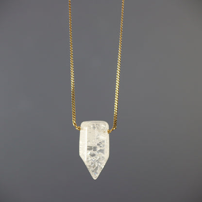 Gold filed  chain Necklace with a clear crystal quartz pendant on a dark gray background